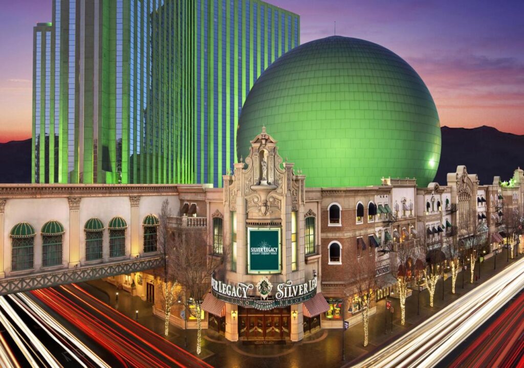 Iconic Silver Legacy casino hotel exterior with green orb and building lights at sunset