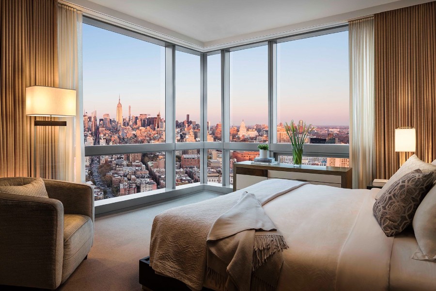 Luxury guest room at The Dominick Hotel in SoHo NYC with bed and huge floor to ceiling windows overlooking the city