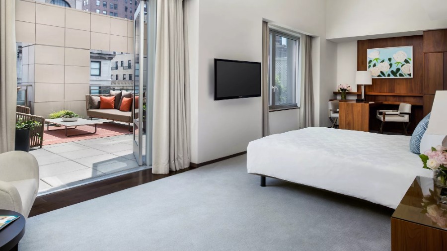 Luxury 5 star guest bedroom leading out to terrace with furniture at The Langham NYC