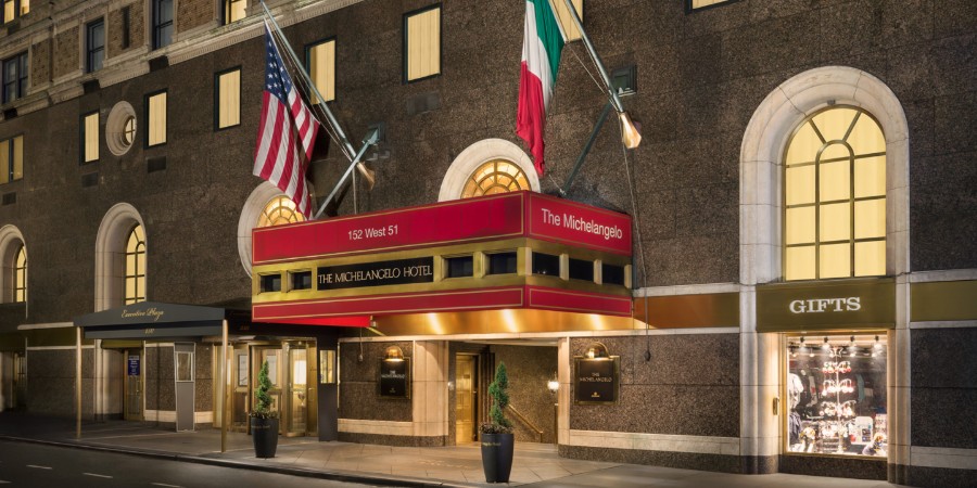 Exterior photo of The Michelangelo Hotel in New York at night with flags flying