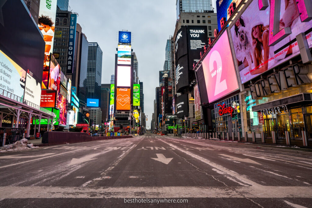 Times Square in NYC empty at dawn with bright lights and road markings clear